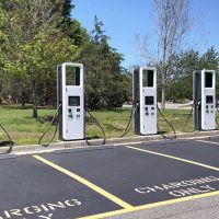 electric charging station with many electric chargers and a parking lot on a sunny day.